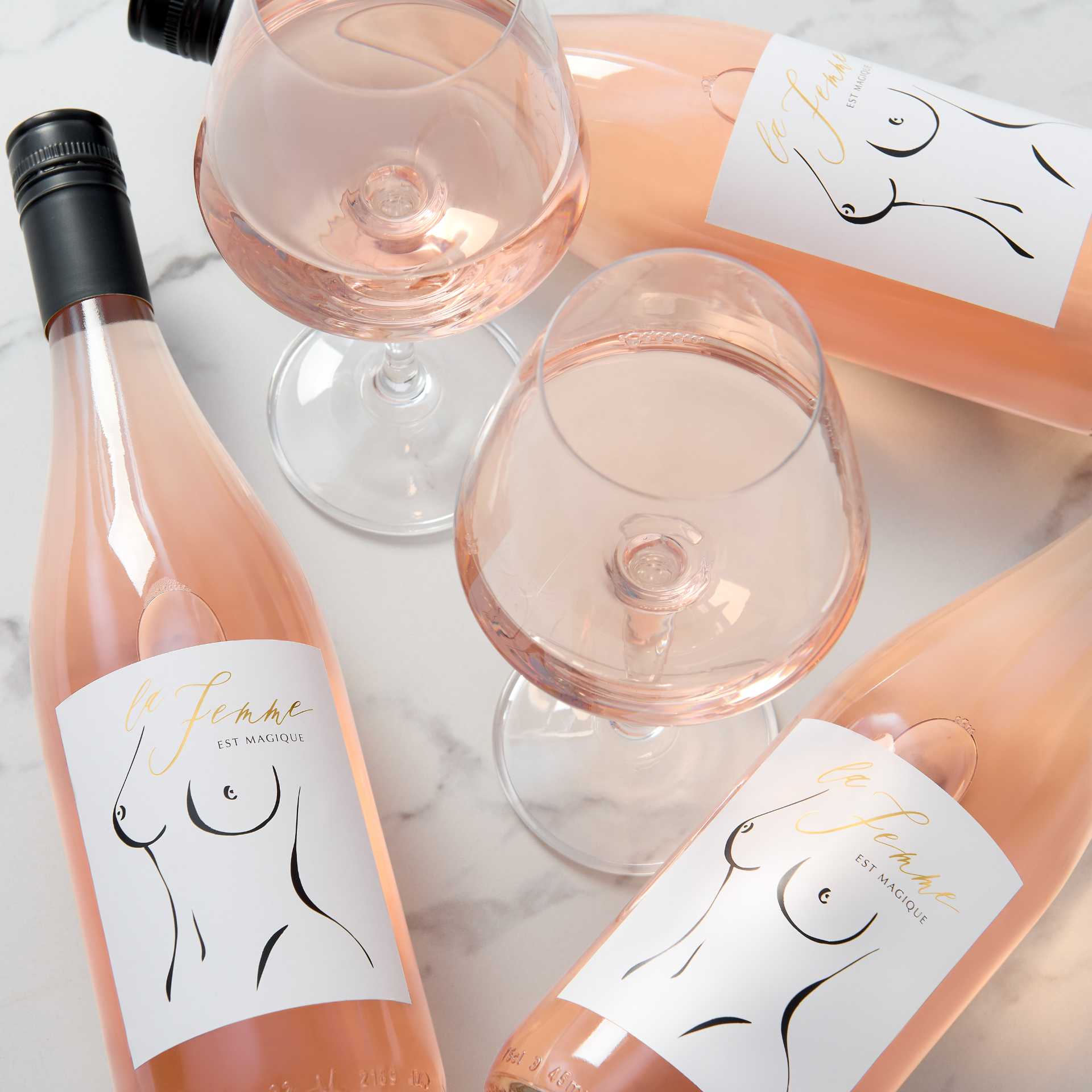 La Femme est Magique rosé bottles and poured glasses on a marble surface